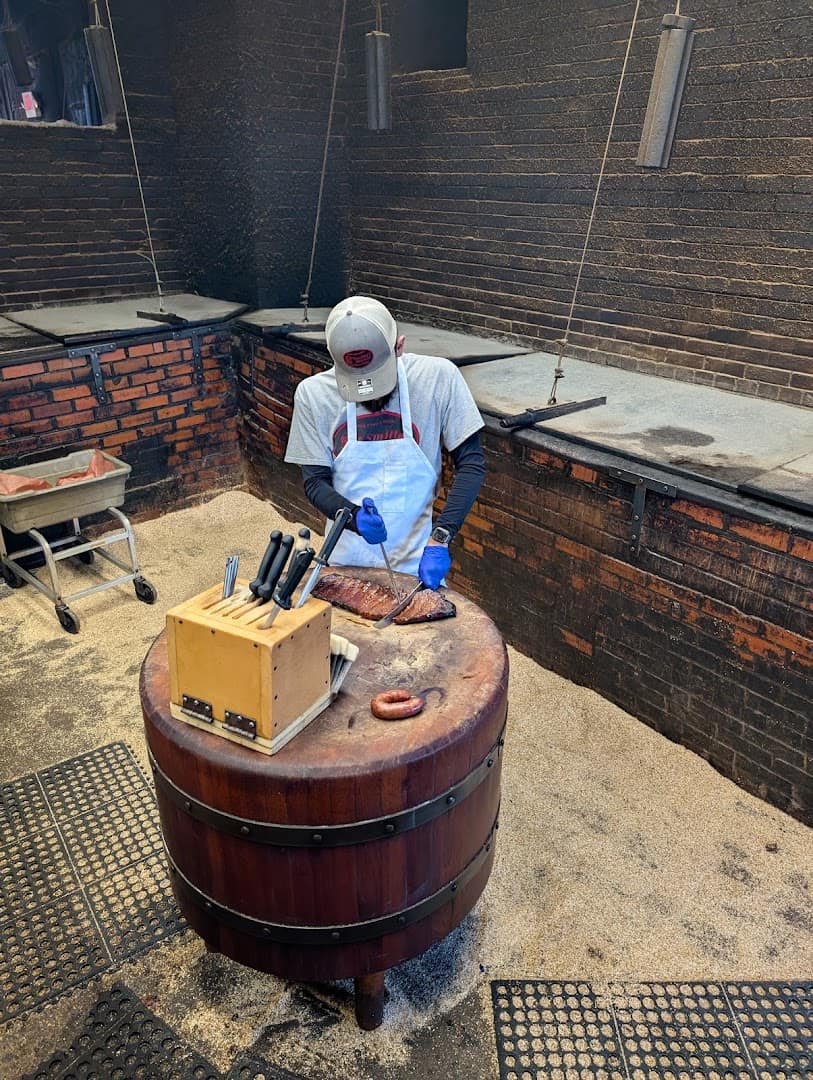 A pitmaster slicing smoked brisket at the pit at Smitty's Market in Lockhart, Texas