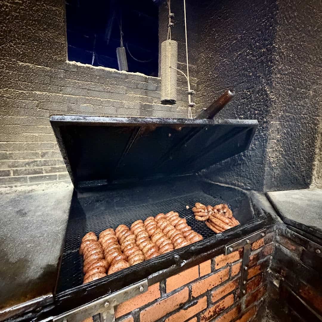 Rings of smoked sausage cooking on the open brick pit at Smitty's Market in Lockhart, Texas