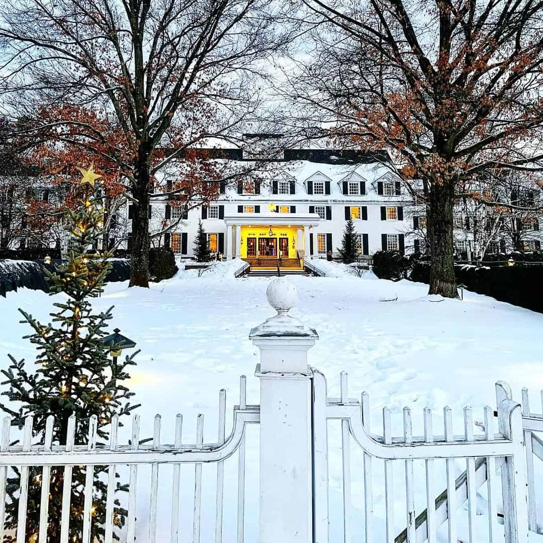 The white Woodstock Inn under fresh snow with a lit Christmas tree at the front gate in Woodstock, Vermont