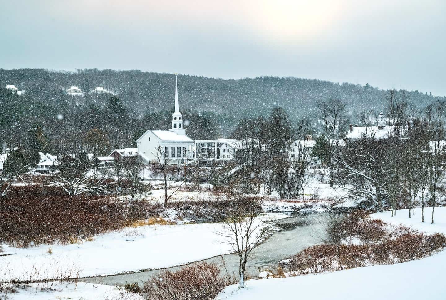 Snow falling over the white church steeple and village of Stowe, Vermont in winter