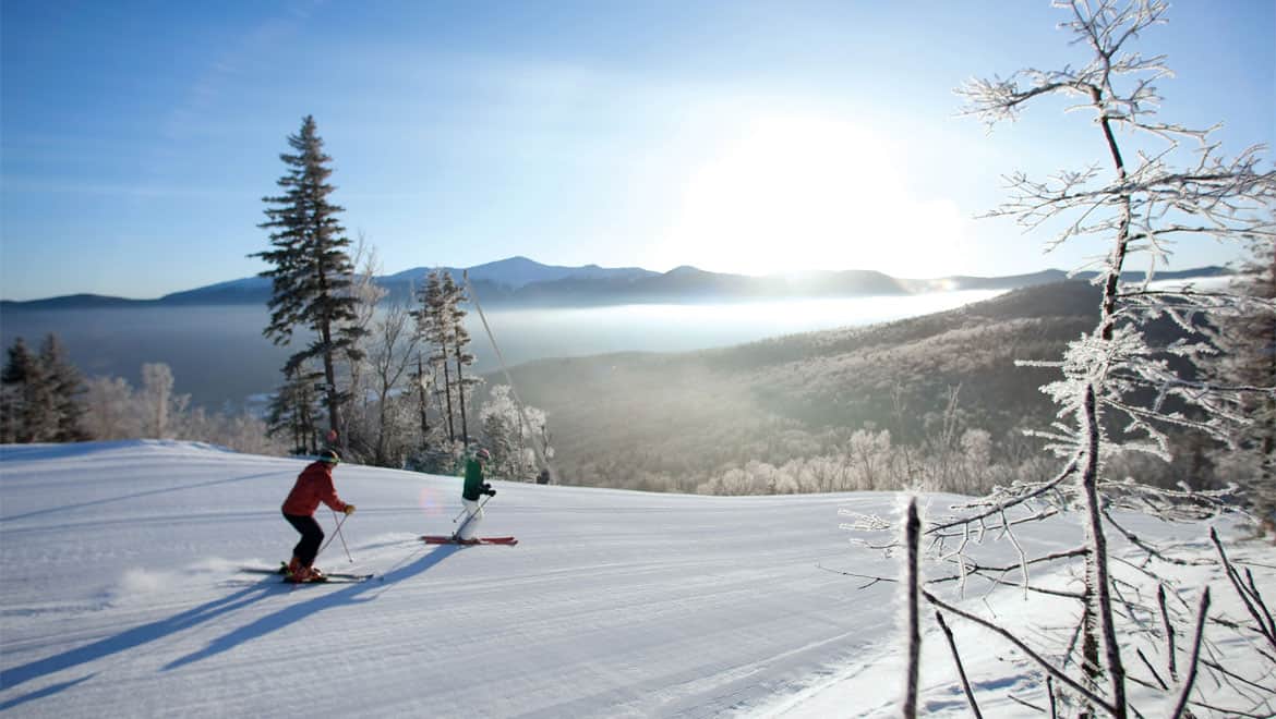 A skier on a snow-covered slope with frosted trees and a misty valley at Bretton Woods, New Hampshire