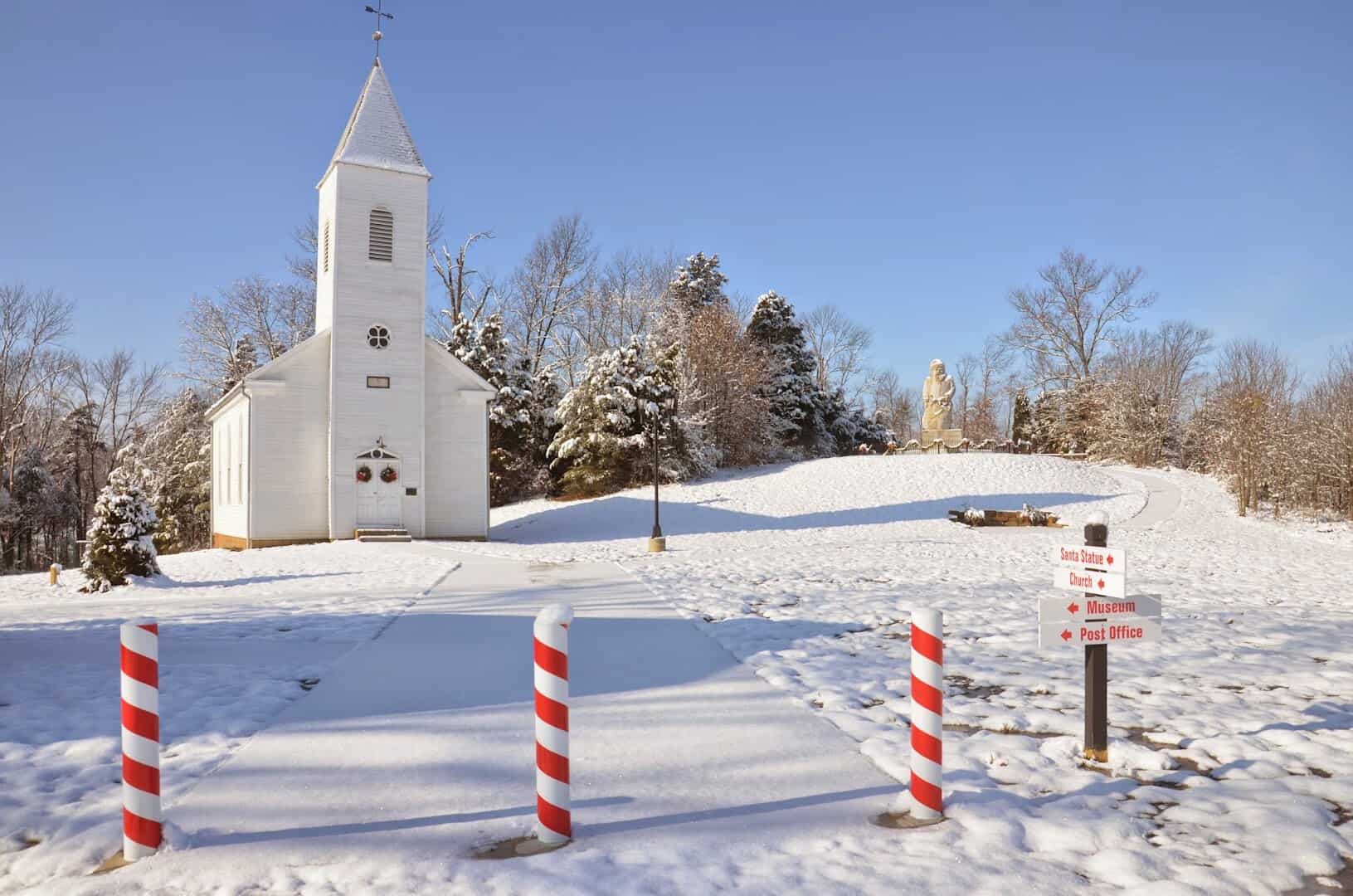 A white-steepled church in the snow with candy-cane posts, Santa Claus, Indiana