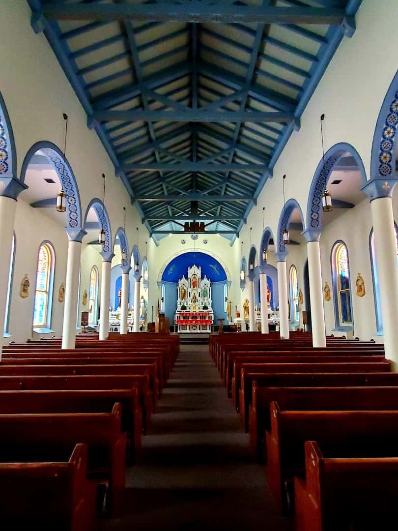 Nave of St. Anthony Catholic Church in Bryan with painted blue arches and wooden pews