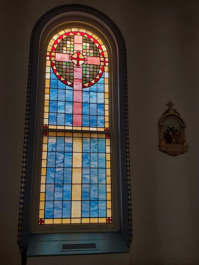 Round arched stained glass window with a cross at St. Anthony Catholic Church in Bryan