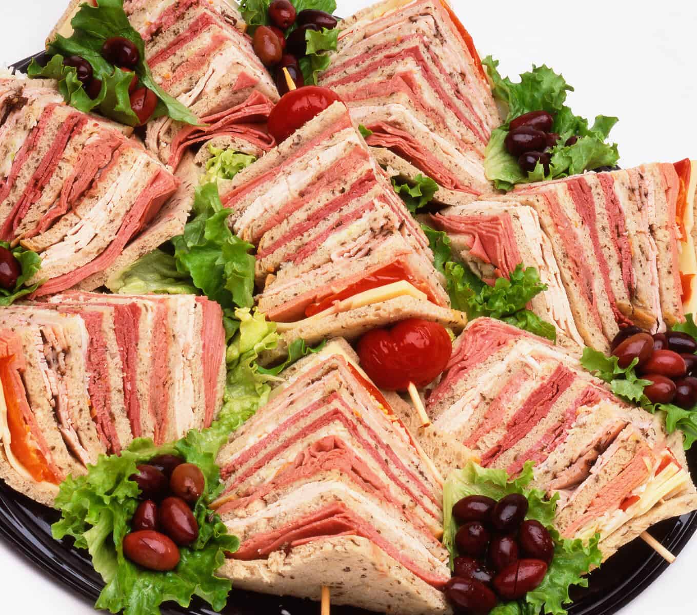 Stacked deli sandwich quarters piled with pastrami and corned beef at Kenny & Ziggy's in Houston