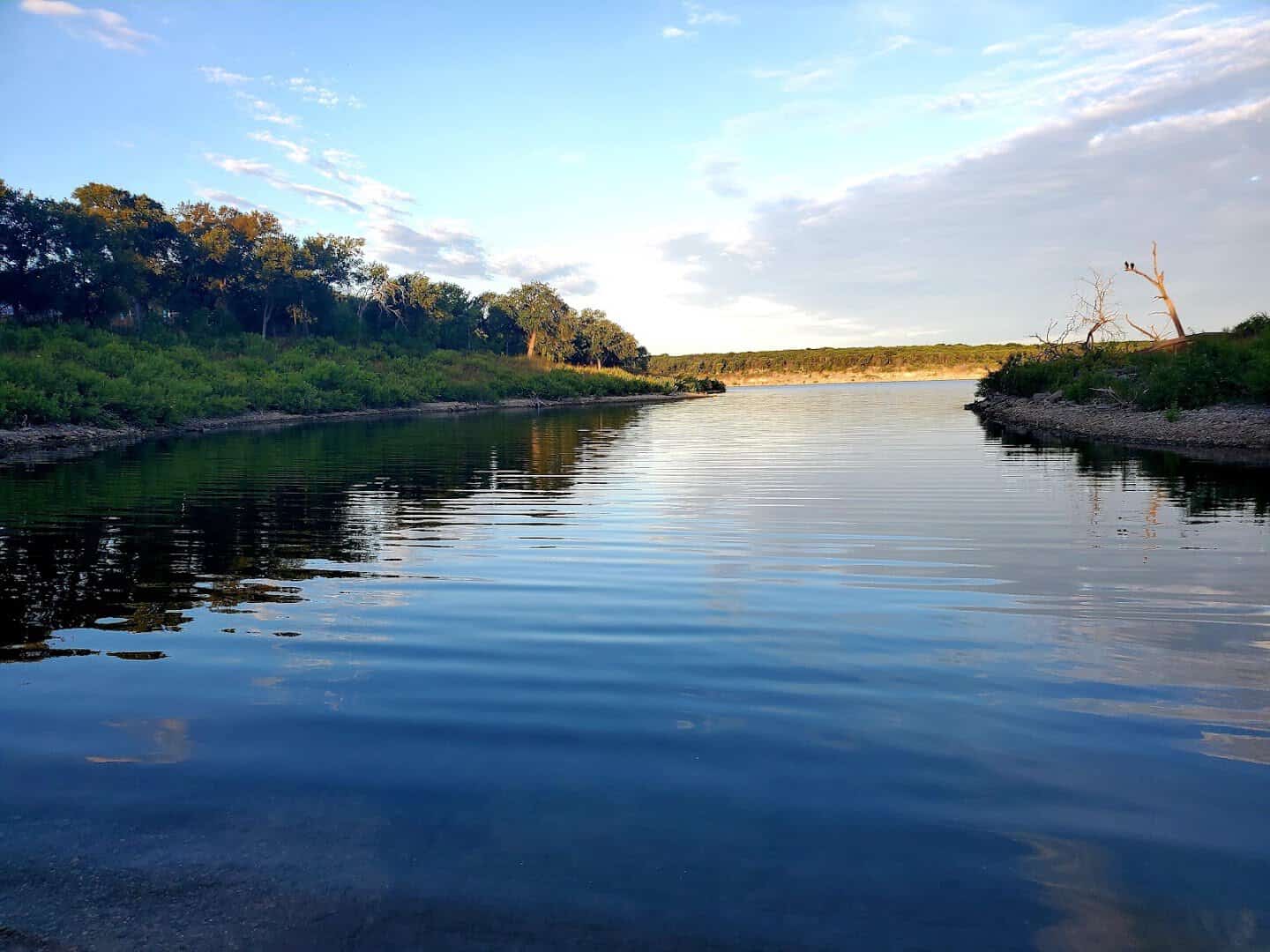 A still, glassy cove on Belton Lake at golden hour
