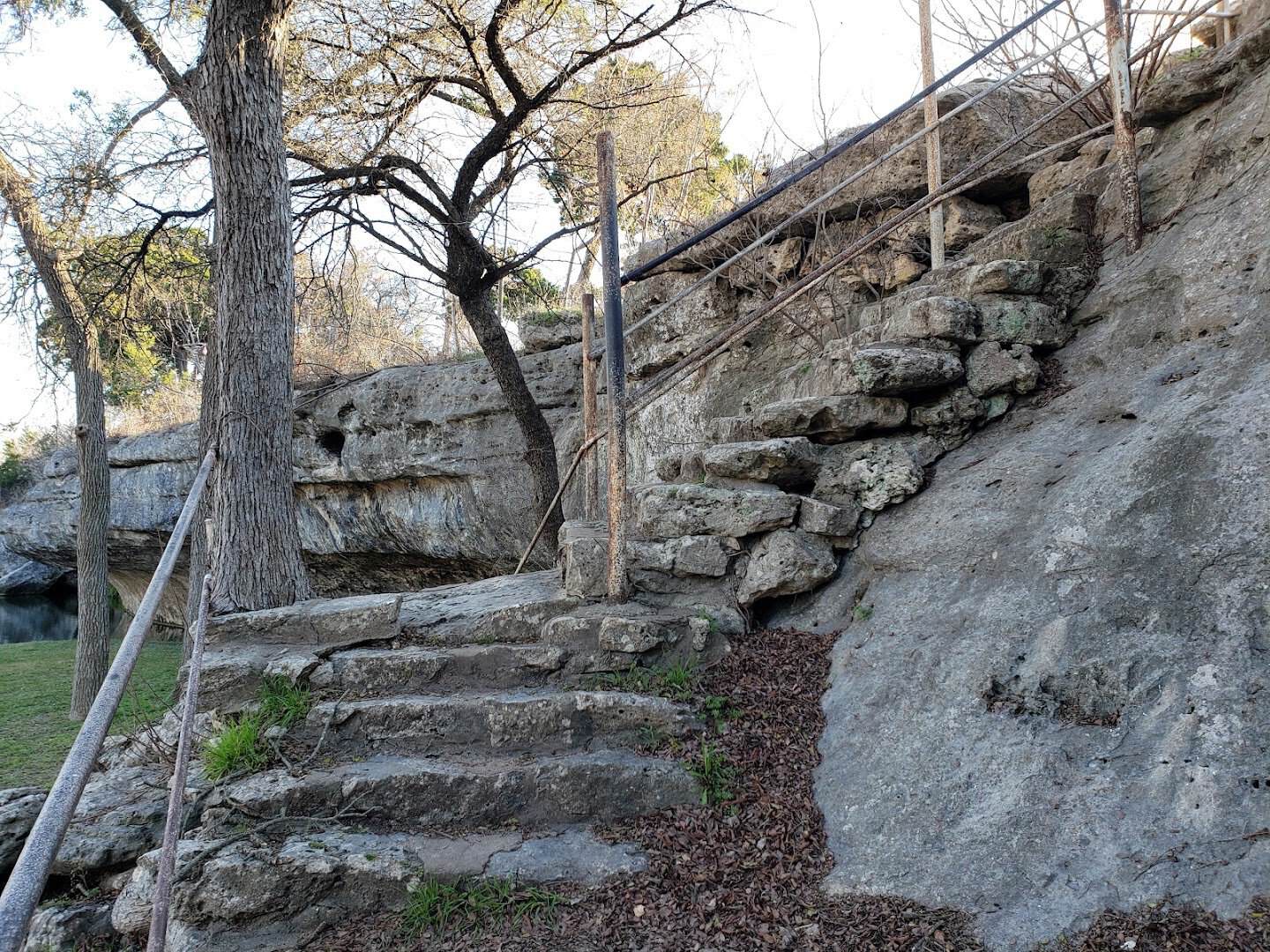 Stone steps cut into the rock wall leading down toward the water at Tonkawa Falls City Park