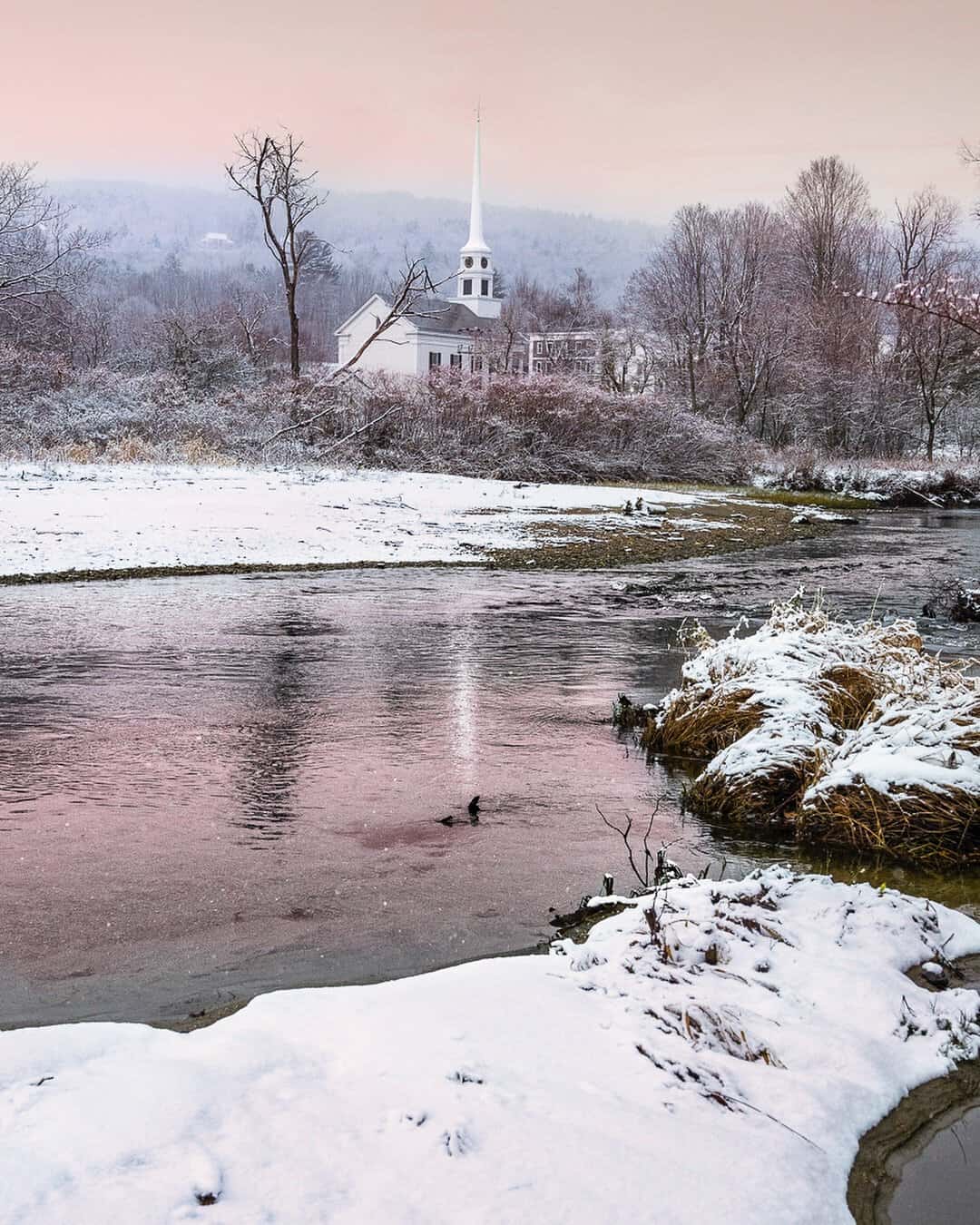 Stowe Community Church white steeple over a snowy river in Stowe, Vermont