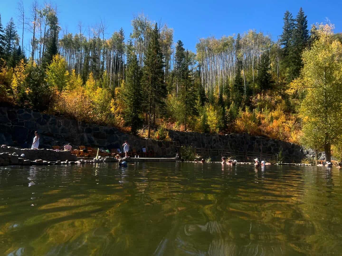 The stone-masonry soaking pools of Strawberry Park Hot Springs ringed by autumn aspens near Steamboat Springs, Colorado