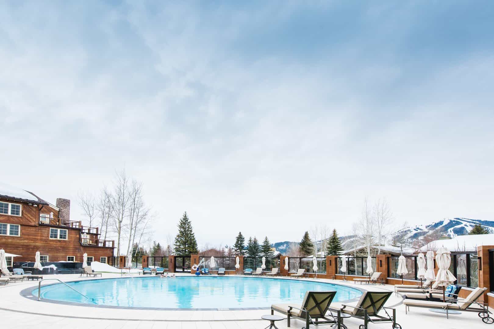 Steaming outdoor pool ringed by snow with Bald Mountain behind at Sun Valley Resort, Idaho