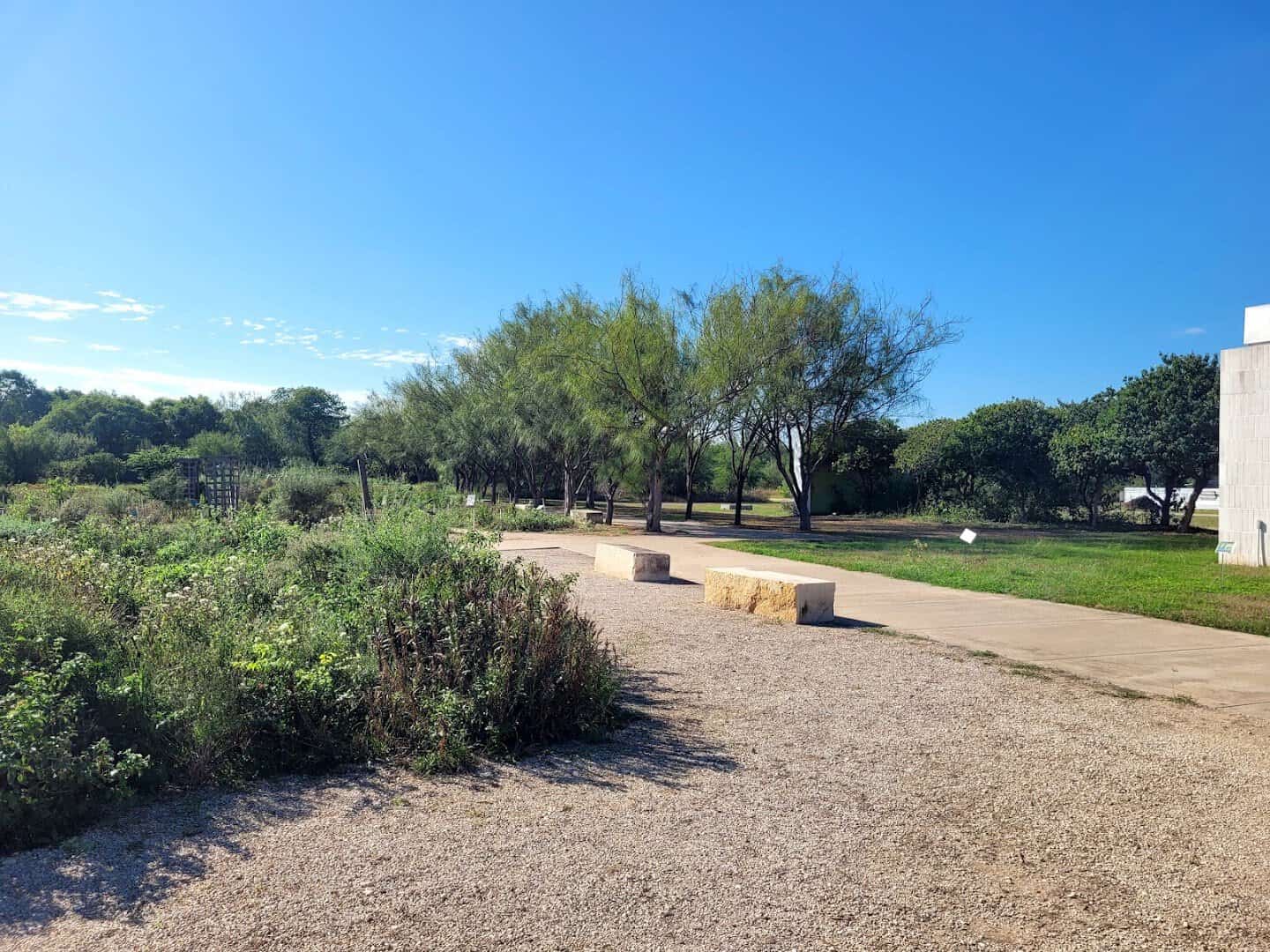 A sunny gravel trail winding through the National Butterfly Center preserve in Mission, Texas