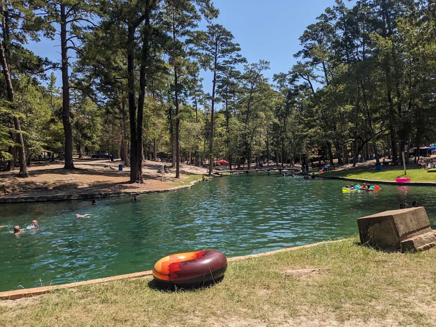 Swimmers and a float enjoying the cool spring water at Camp Tonkawa Springs