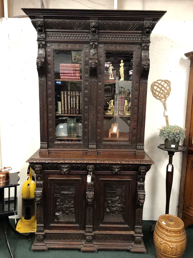 Tall carved antique bookcase cabinet in a booth at The Antique Gallery of Houston in Spring Texas