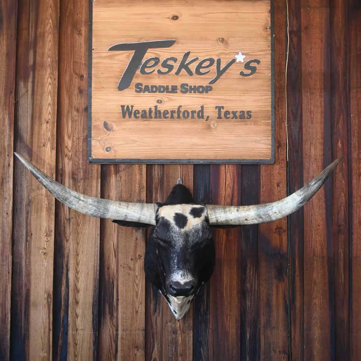 Teskey's Saddle Shop wooden sign above a mounted longhorn in Weatherford, Texas