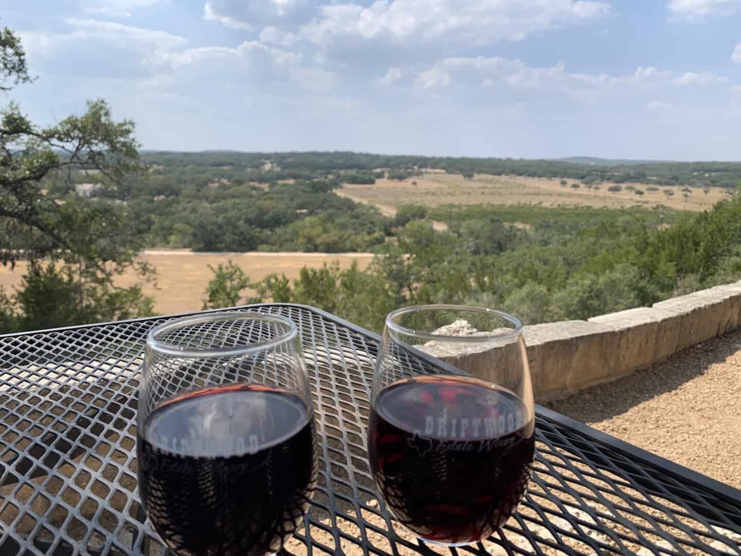 Two glasses of red wine on a table overlooking the Hill Country vineyard near Driftwood