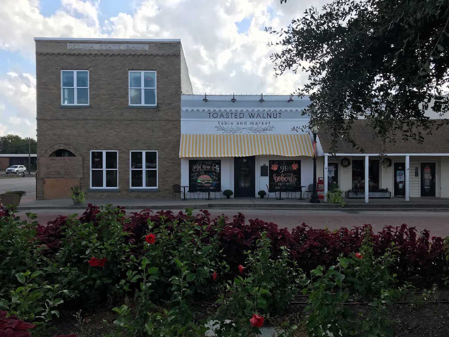 Toasted Walnut Table and Market storefront with roses out front on the Celina square