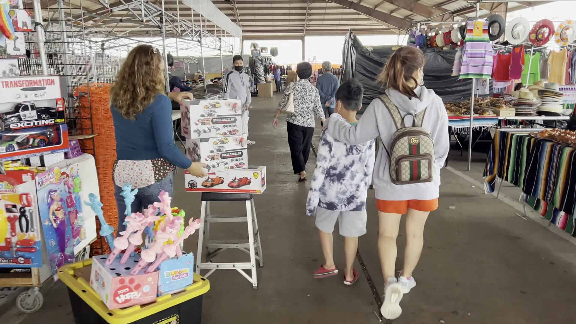 Shoppers browsing toy and clothing stalls in the covered market at Traders Village in Grand Prairie, Texas