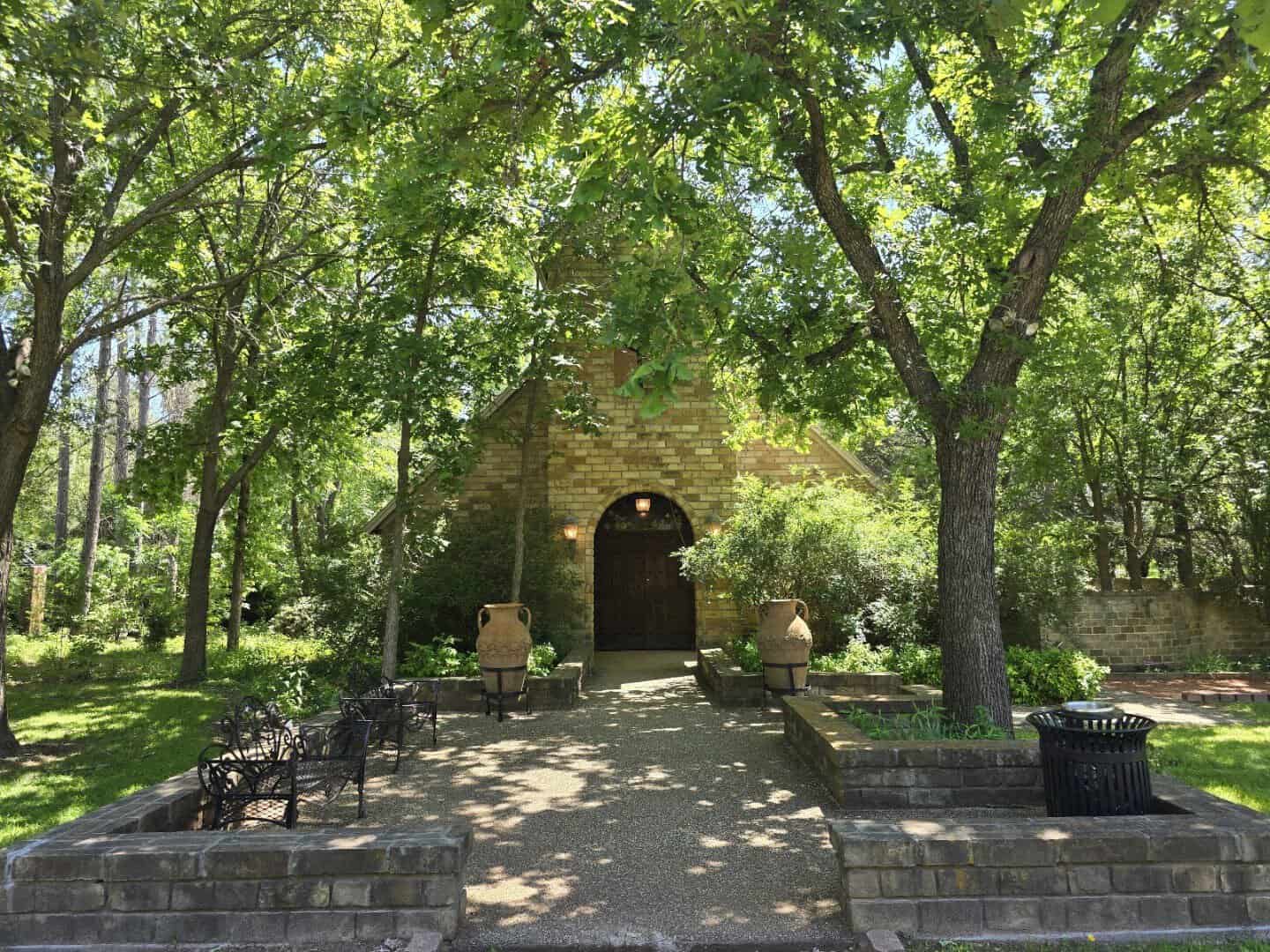 Tree-lined lawn with shaded benches at Clark Gardens in Weatherford, Texas