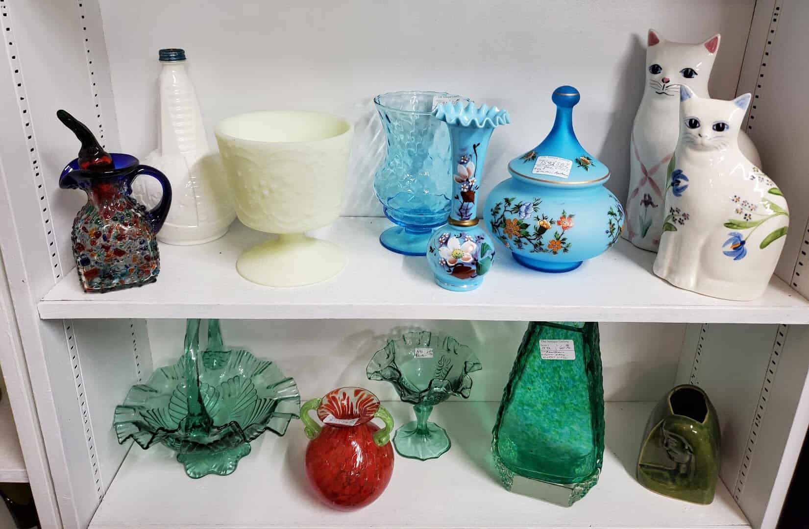 Shelf of vintage blue and green art glass at The Antique Gallery of Houston in Spring Texas