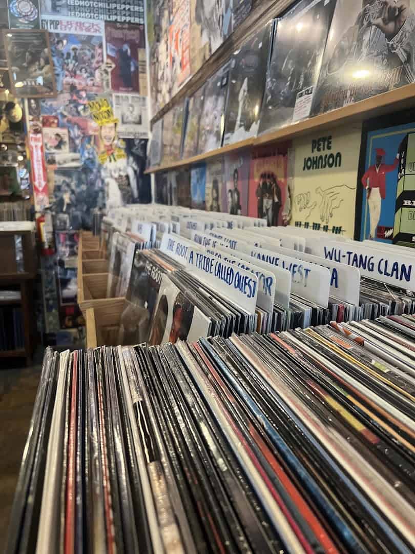 Crate of vinyl with genre dividers beside a wall of records at Sigs Lagoon in Houston