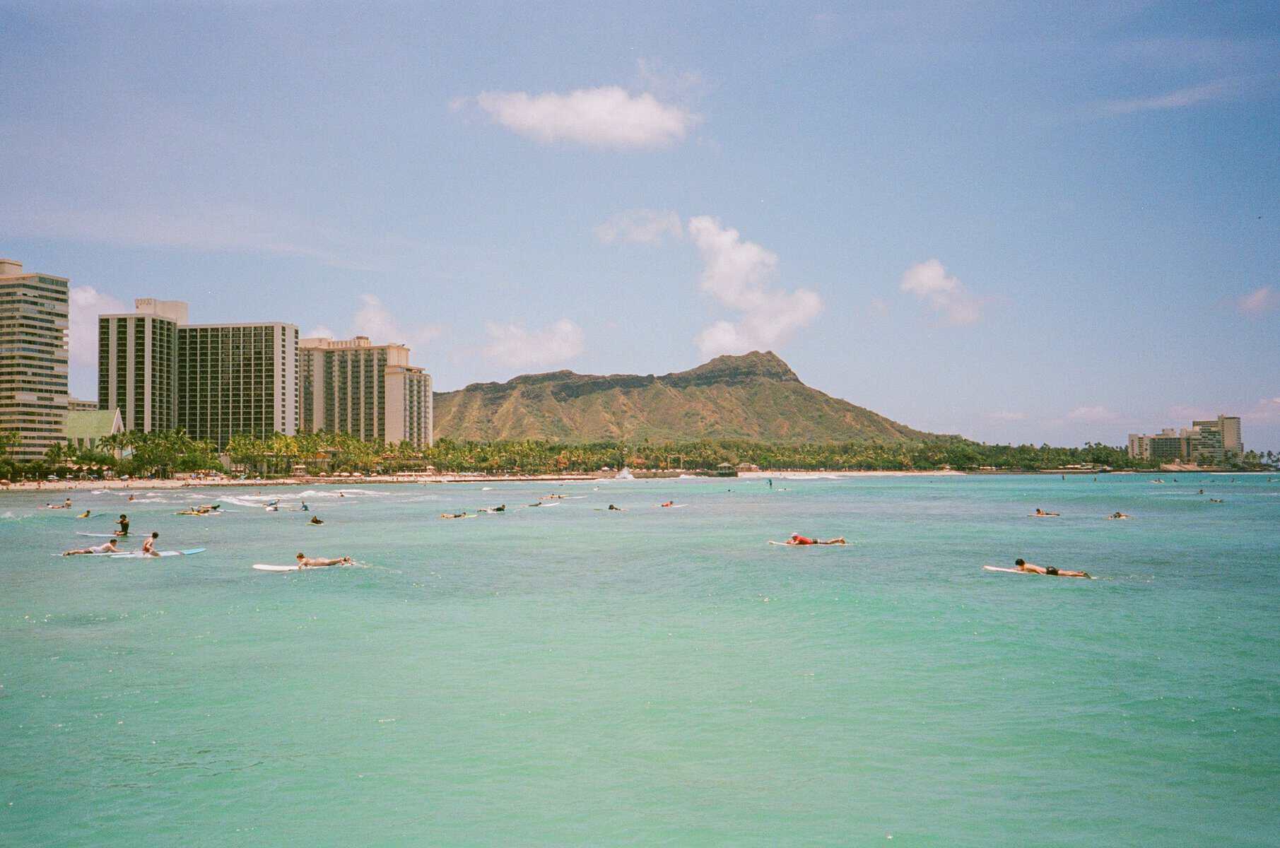 Surfers in the lineup with Diamond Head rising over Waikiki Beach, Honolulu, Hawaii