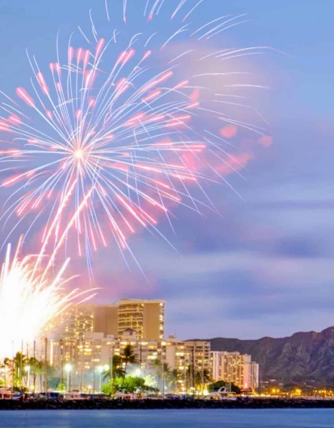 Fireworks bursting over the lit Waikiki skyline and Diamond Head at night, Honolulu, Hawaii