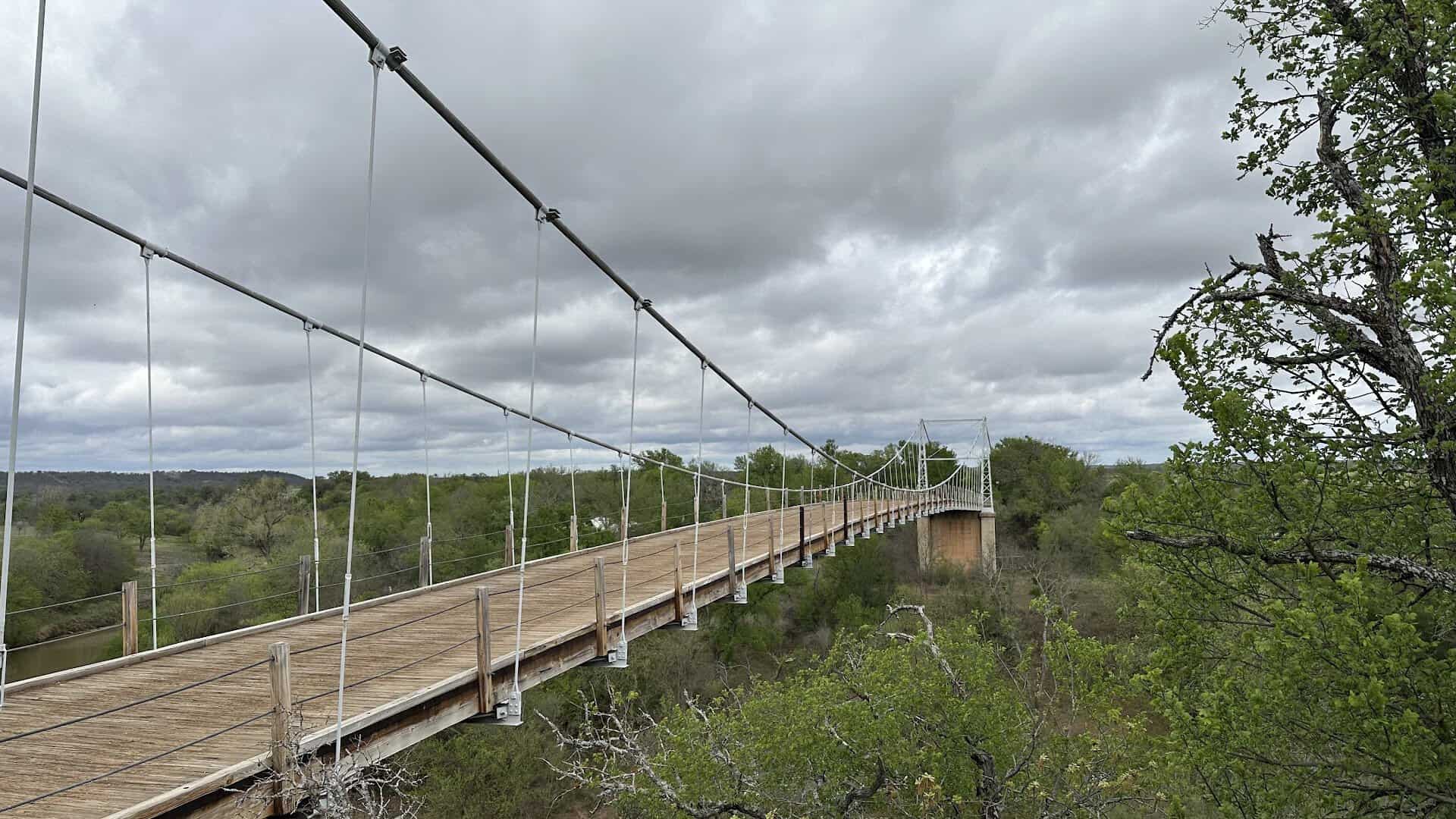 Walking the plank deck of the Regency Suspension Bridge above the Colorado River in Texas