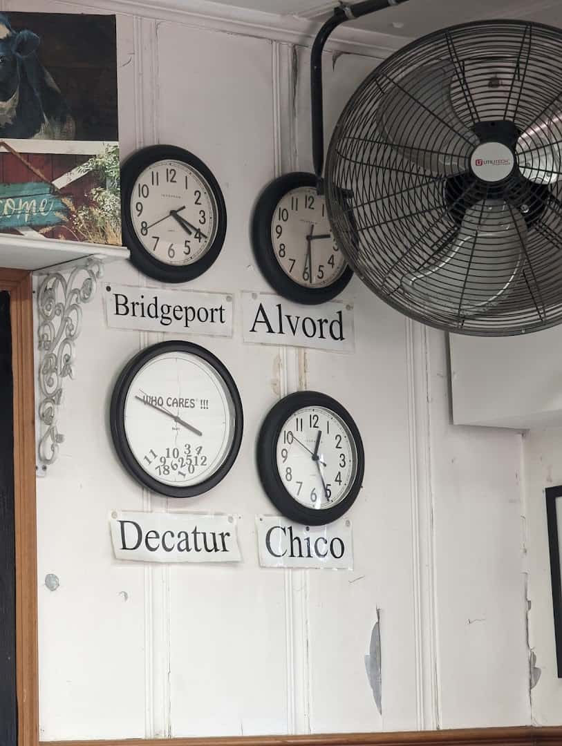 Wall of clocks named for nearby towns inside Whistle Stop Cafe in Decatur, Texas
