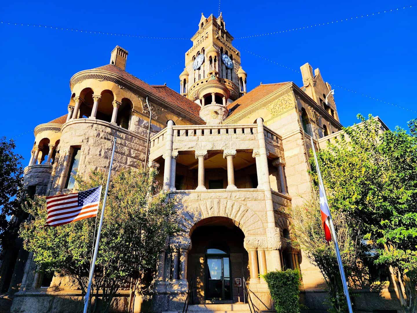 The Wise County Courthouse rising over the Decatur town square with US and Texas flags