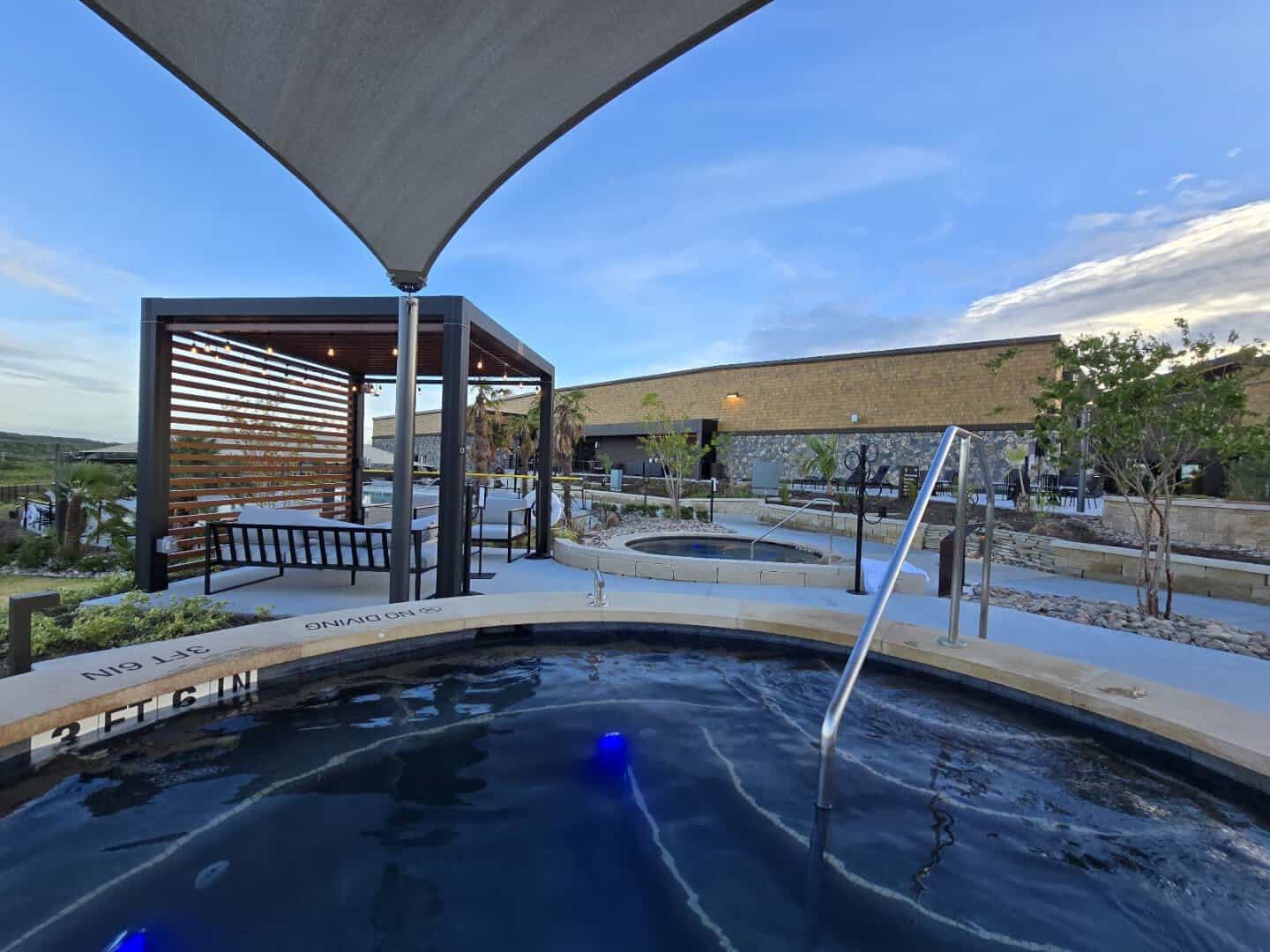 Soaking pool framed by a timber pergola and stone landscaping at WorldSprings